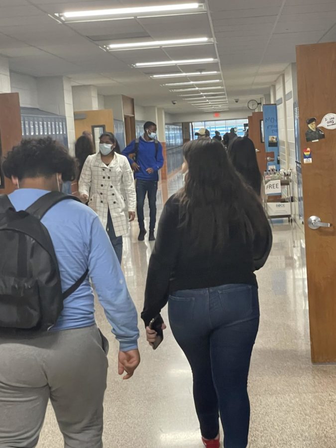 Students walking in the halls while keeping their masks up and over their noses.