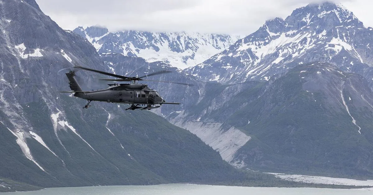 An overturned Cessna 180 on a coastal sandbar with rescue crews nearby in Alaska
